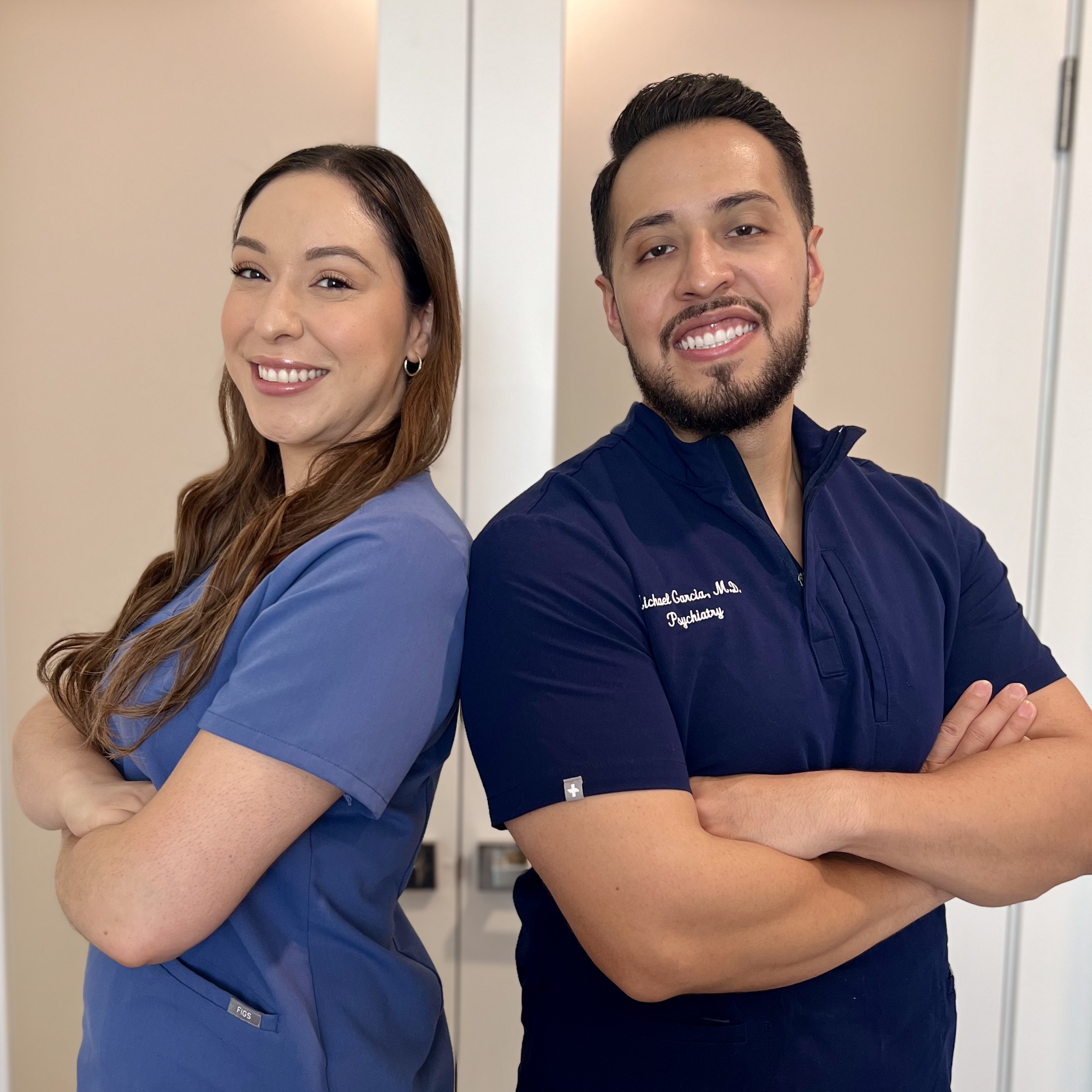 Dr. Michael Garcia and Angelica Parocua standing back to back in scrubs at LUMUS clinic